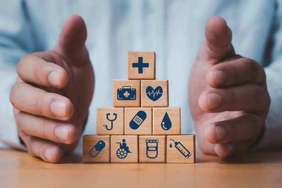 Businessman hand protecting to healthcare icons on wooden block cube for health insurance